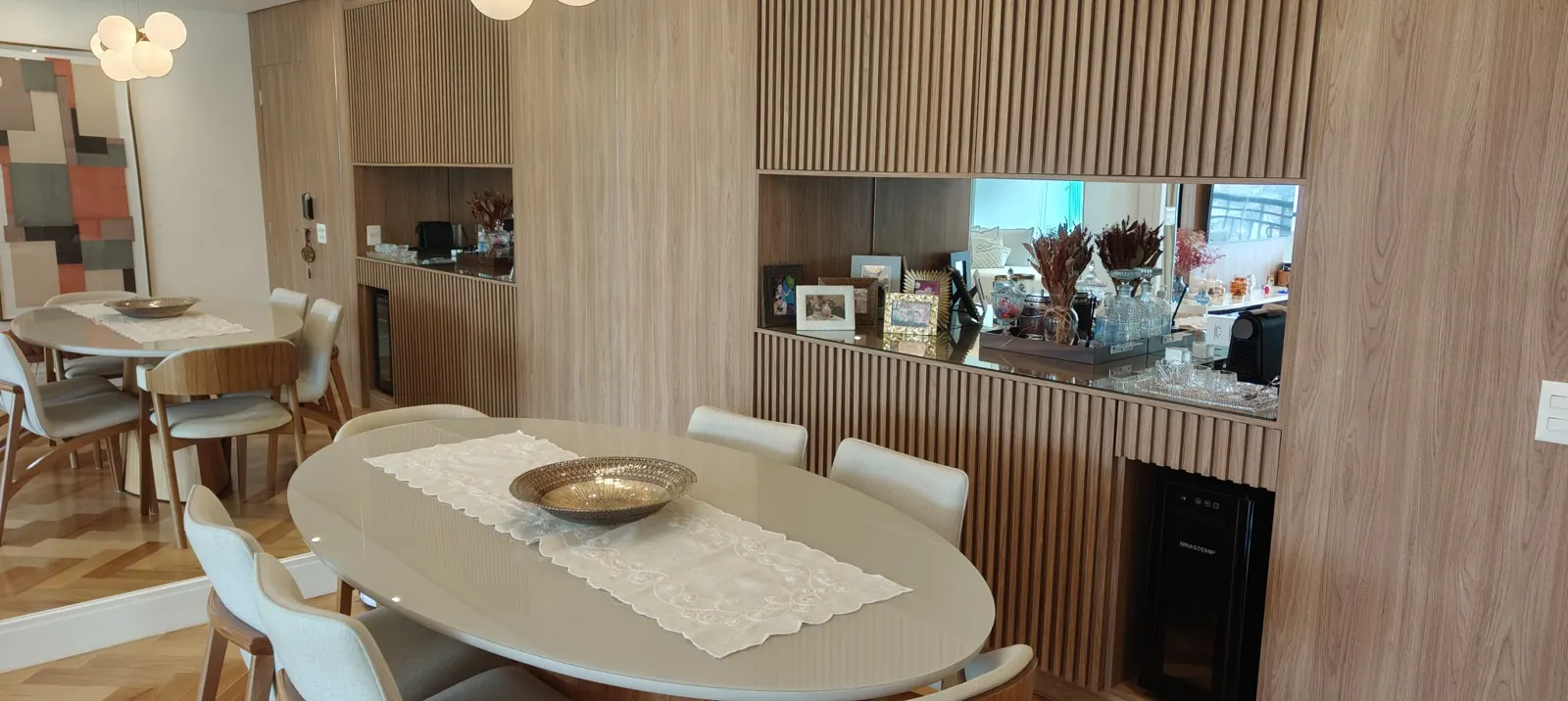 Sala de jantar com mesa clara e painel de madeira